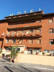 un grande edificio in mattoni rossi con bandiere di Hotel Vico Alto Siena a Siena
