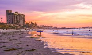 a beach at sunset with a building and people on it at Cozy 1 BR in Historic SD Walk to Restaurants in San Diego