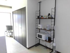 a room with a kitchen with a microwave on a shelf at lineweb Home sapporo803 in Sapporo