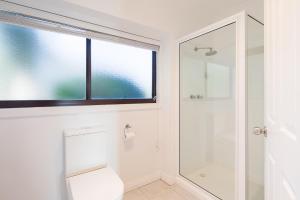 a bathroom with a toilet and a window at Ananda 3 - Bliss by the Sea in Corinella