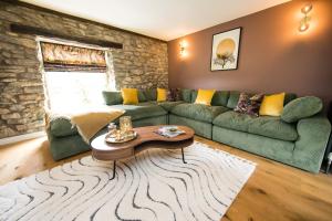 sala de estar con sofá verde y mesa en Candle House By Muse Escapes, en Castleton