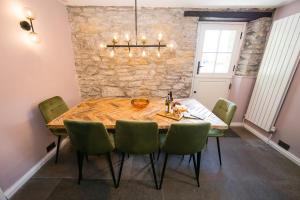 a dining room with a wooden table and green chairs at Candle House By Muse Escapes in Castleton