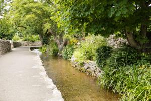a river with a path next to a stone wall at Candle House By Muse Escapes in Castleton