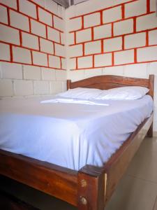 Cama de madera en habitación con pared de ladrillo en Comodo Alojamiento en San cipriano, en San Cipriano