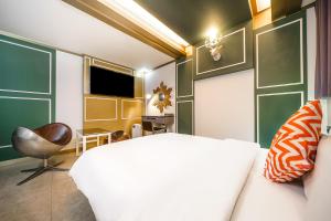 a bedroom with a white bed and a chair at Gongju No 25 Hotel in Gongju