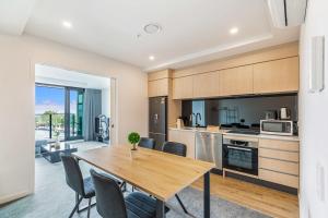 una cucina e una sala da pranzo con tavolo e sedie in legno di Cozy apartment by Eden Park ad Auckland