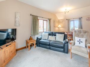 a living room with a blue couch and a chair at Ash Cottage - Uk45581 in Maltby le Marsh