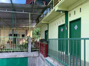 RedDoorz near Pelabuhan Ajibata Parapat في بارابات: مبنى بأبواب خضراء وبلكونة