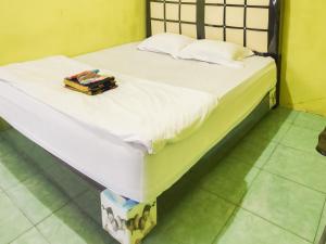 una cama con sábanas blancas y una caja en ella en RedDoorz near Pelabuhan Ajibata Parapat en Parapat