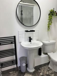 a bathroom with a sink and a toilet and a mirror at Glendale Gardens Apartment in Southend-on-Sea