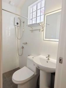 a white bathroom with a toilet and a sink at Private Guest House Bay Breeze in San Juan