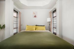 拜縣的住宿－Betel Palm Village - Casa Retreat，一间卧室配有一张带黄色枕头的大型绿色床。