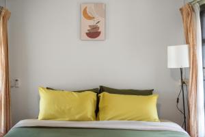 a bedroom with a bed with two yellow pillows at Betel Palm Village - Casa Retreat in Pai