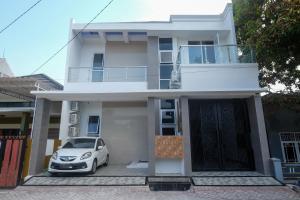 Un coche blanco aparcado delante de una casa en RedDoorz Syariah @ Tlogosari Semarang, en Alastuwo
