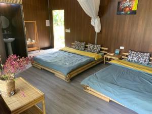 a bedroom with two beds and a table and a mirror at Luong Son Homestay Ecolodge in Cao Bằng
