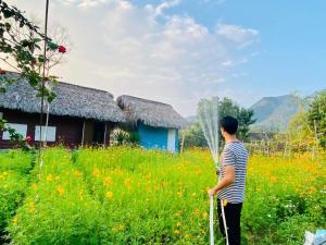 a man standing in a field with a cane at Luong Son Homestay Ecolodge in Cao Bằng