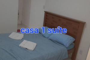 Bett mit blauem Schild darüber in der Unterkunft Areia Branca Casas / casa 1. in Cabo Frio