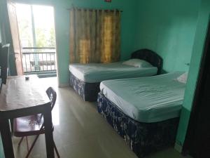 a room with two beds and a table and a window at OYO 93306 Rinjani Guest House in Balikpapan