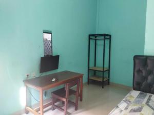 a room with a desk and a chair and a bed at OYO 93306 Rinjani Guest House in Balikpapan