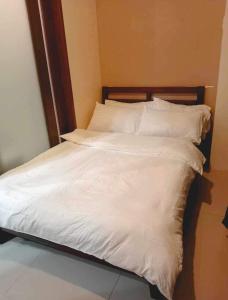 ein weißes Bett mit weißer Bettwäsche und Kissen in der Unterkunft Casa De Familia Staycation in Manila