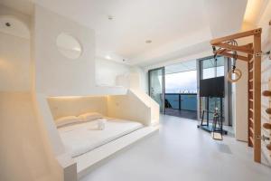 a white bedroom with a bed and a large window at Sanya Phoenix Island Yuejia flat in Sanya