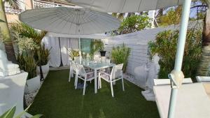 stół z krzesłami i parasol na patio w obiekcie White Sunset - Votre appartement pieds dans l'eau w mieście Trois Bassins