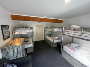 a room with three bunk beds and a couch at Peppertree Lodge & Backpackers in Paihia