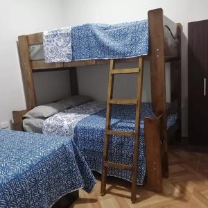 ein Etagenbett mit einer Leiter neben einem Bett in der Unterkunft MERINO HOUSE COLAN BEACH in Paita