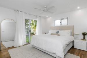 a white bedroom with a large bed and a window at Pool House - Peaceful Luxury, Byron Bay in Byron Bay +8 photos