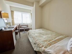 a hotel room with a bed and a desk with a computer at Ichihara Marine Hotel in Ichihara