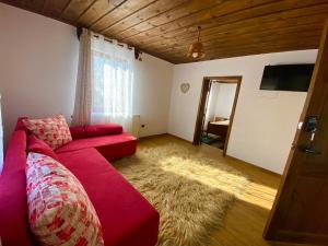 a living room with a red couch and a rug at Къща за гости Близнаците in Leshten