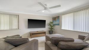 uma sala de estar com 2 sofás e uma televisão de ecrã plano em Hooked On Hibbard em Port Macquarie