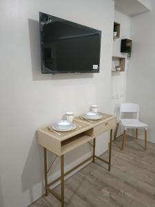 a room with a table and a tv on a wall at Minimalist Condo Studio at Messavire Garden Residence near Ruins Bacolod in Bacolod