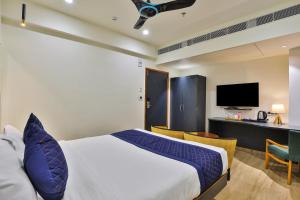 a bedroom with a bed and a desk with a tv at FabHotel Prime Empyrean in Gandhinagar