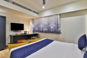 a hotel room with a bed and a tv at FabHotel Prime Empyrean in Gandhinagar