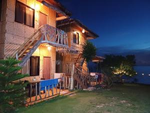 a house with a deck with a table and chairs at Almare Guest House Siquijor in San Juan