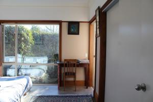 1 dormitorio con cama, ventana y mesa en Hadlow Sunrise Retreat, en Timaru