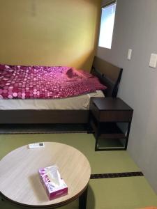 和歌山市にあるサナ イン タウンのテーブルとベッド付きの小さな部屋