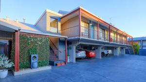 a building with a car parked in a parking lot at The Cottage Motor Inn Albury CBD in Albury
