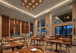 a restaurant with wooden tables and chairs and windows at Hyatt Place Bodh Gaya in Bodh Gaya
