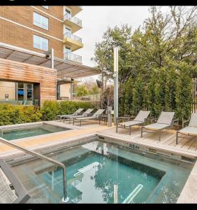 Luxurious & cozy 2bedroom/2bath apt downtwn Dallas في دالاس: مسبح مع كرسيين ومبنى