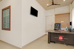 ein Büro mit einem Schreibtisch und einem TV an der Wand in der Unterkunft OYO Flagship R V Palce in Gorakhpur