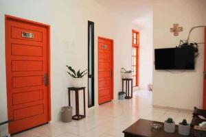 salon z dwoma czerwonymi drzwiami i telewizorem w obiekcie OYO 93311 Pesona Orange Homestay w mieście Padang