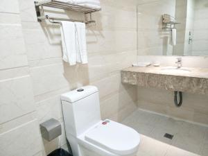 a white bathroom with a toilet and a sink at Harbin Huaxi Hotel - Ice World Branch in Harbin