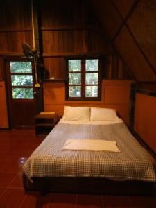 a large bed in a room with two windows at Pai Kiniman Resort in Pai
