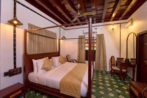 a bedroom with a bed and a desk and a table at Malabar Kovilakam in Malappuram