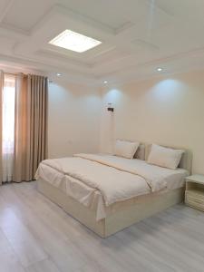 サマルカンドにあるDARI-ZANJIR family guest houseの白い部屋に大型ベッド1台が備わるベッドルーム1室が備わります。