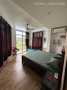 a bedroom with a bed and a large window at Dhauladhar Homes in Dharamshala