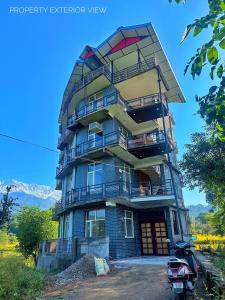 a tall building with balconies and a scooter parked in front at Dhauladhar Homes in Dharamshala