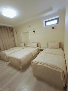 two beds in a hotel room with a window at Hotel DARI-ZANJIR family guest house in Samarkand